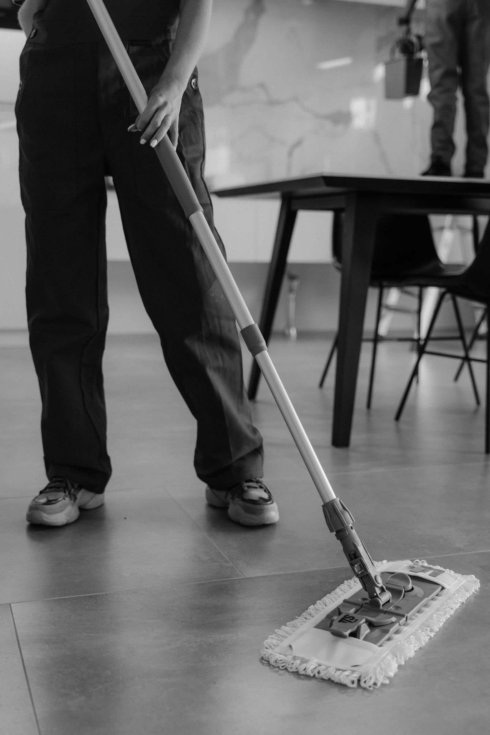 Cleaner wiping down desks in a small modern office